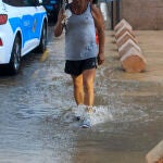 Una persona vadea una calzada anegada por la lluvia
