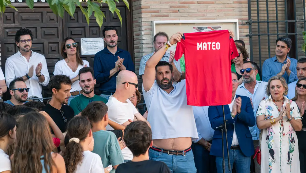 Varios familiares y amigos del niño asesinado muestran una camiseta con su nombre, durante el minuto de silencio en la puerta del Ayuntamiento de Mocejón, Toledo
