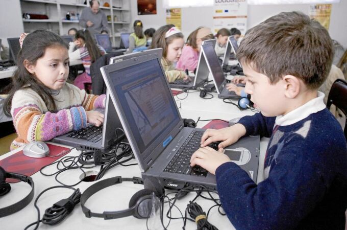 Niños y niñas ante sus ordenadores portátiles en el colegio