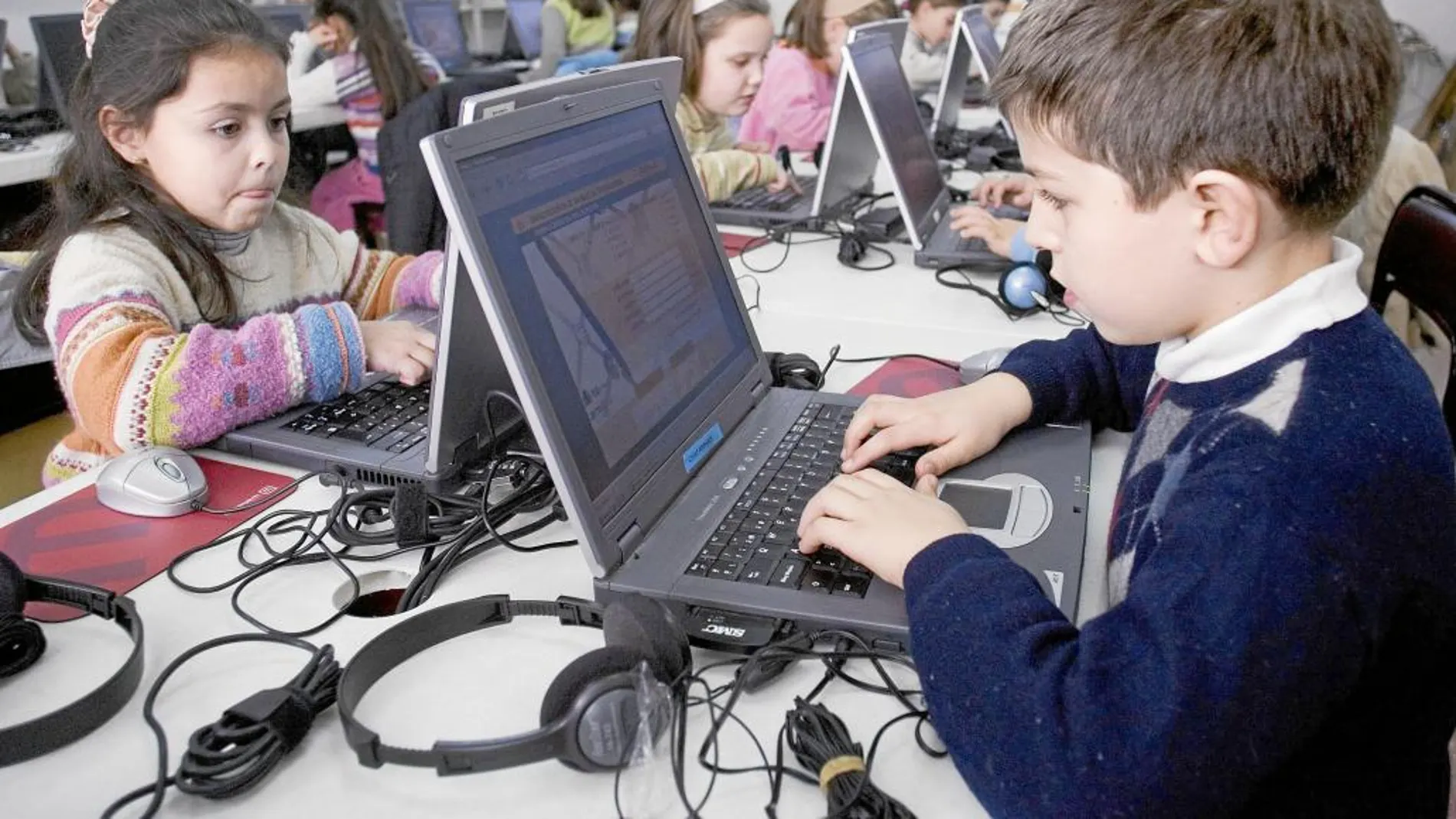 Niños y niñas ante sus ordenadores portátiles en el colegio