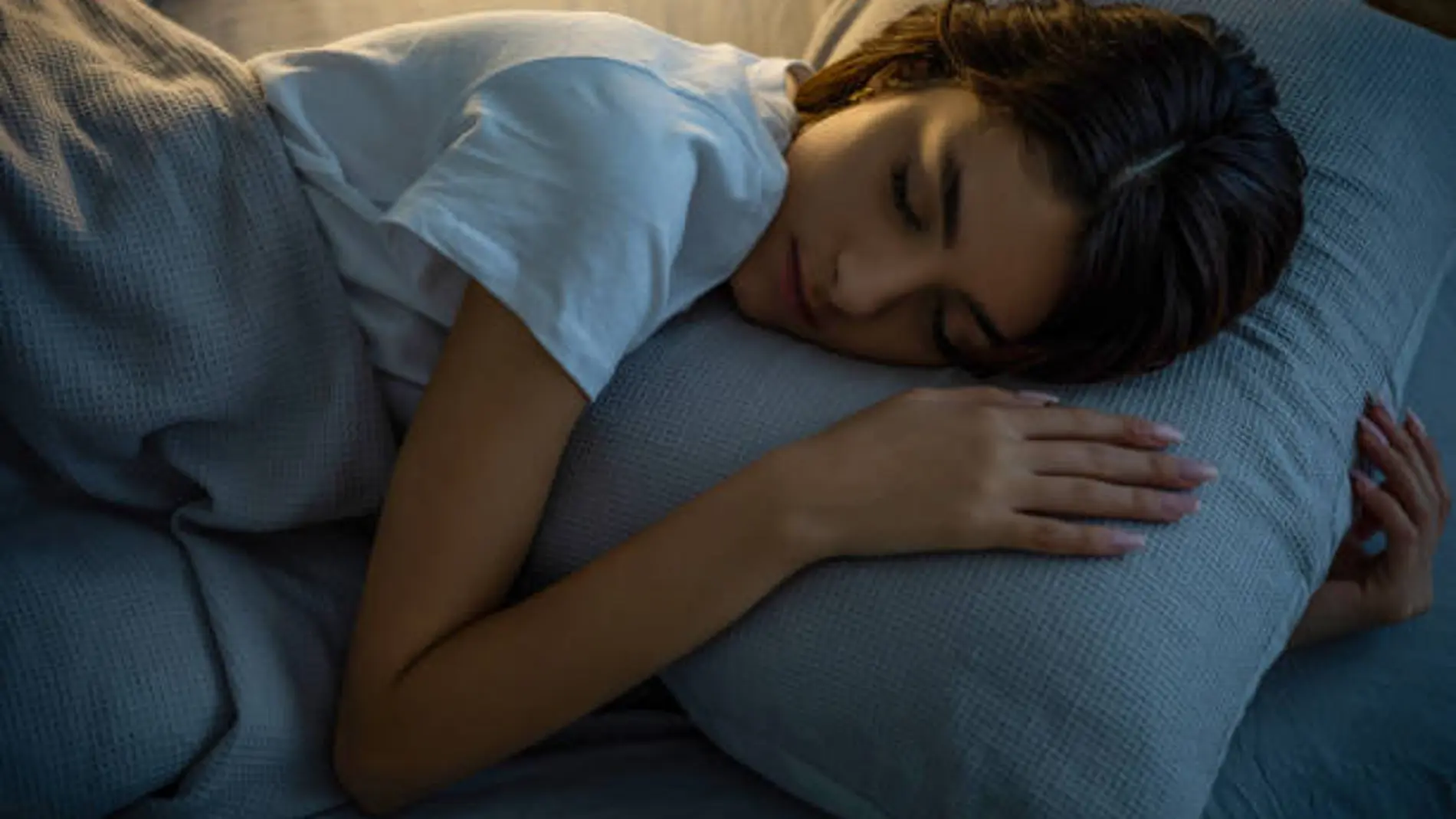 Una joven duerme abrazando una almohada