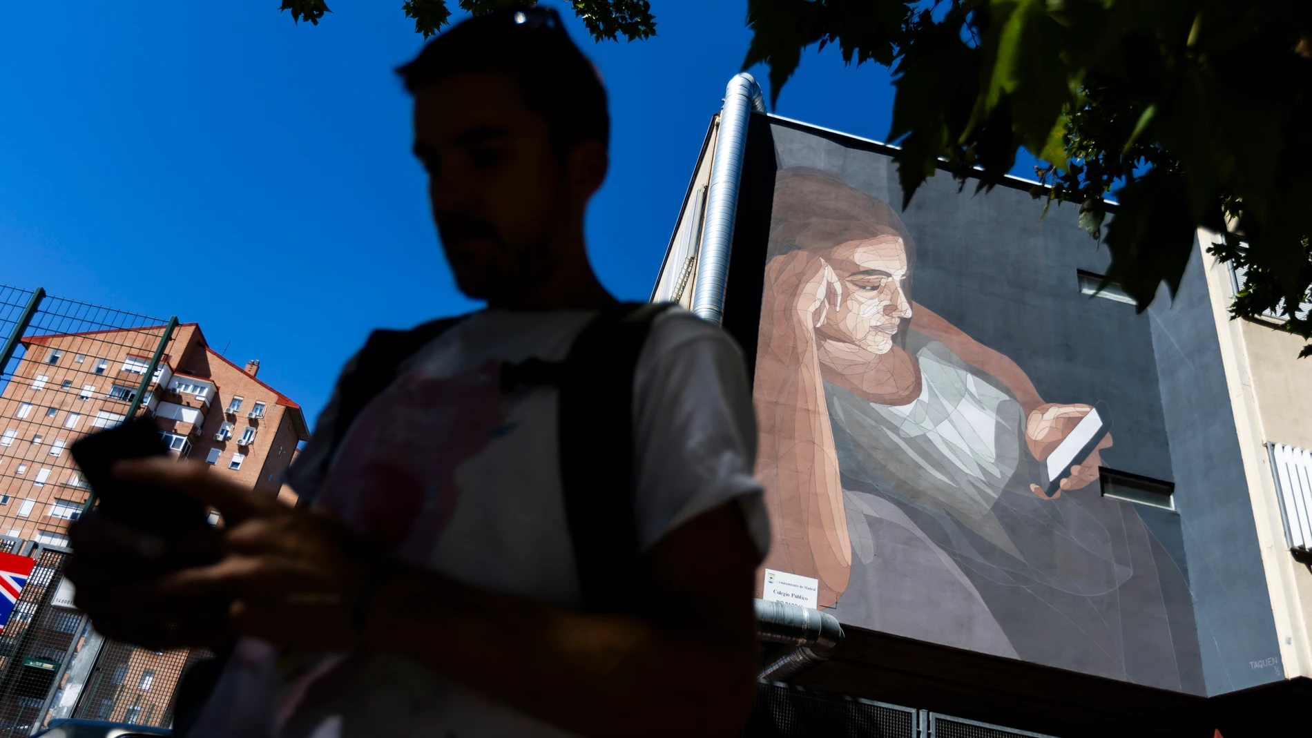 El artista gallego Taquen, junto a su obra, en el Colegio Pío Baroja de Moratalaz
