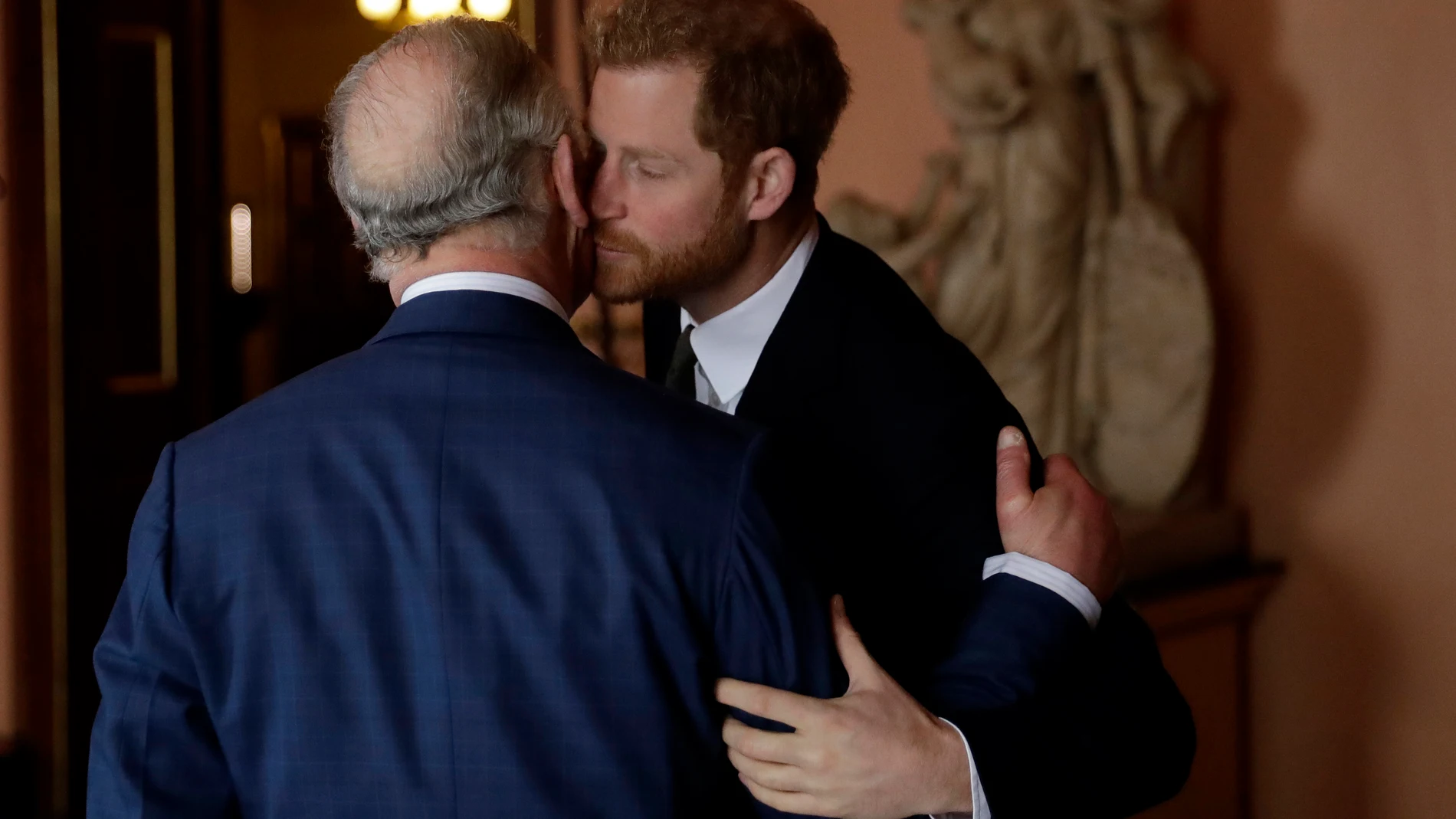Britain's Prince Harry kisses and greets his father Prince Charles upon their separate arrival to attend a coral reef health and resilience meeting with speeches and a reception with delegates at Fishmongers Hall in London, Wednesday, Feb. 14, 2018. (AP Photo/Matt Dunham, Pool, File)