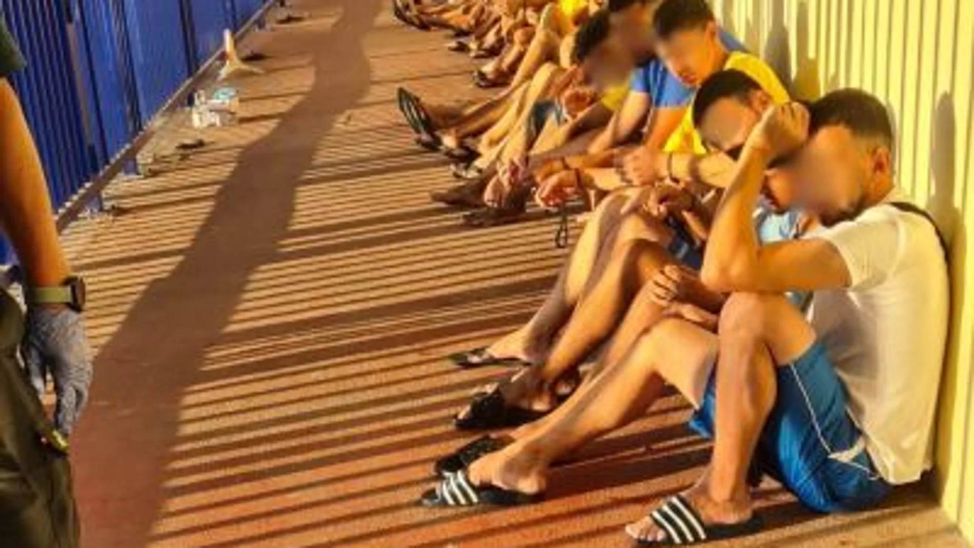 Un grupo de inmigrantes es custodiado por la Guardia Civil en la frontera del Tarajal, tras ser interceptados cruzando a nado y bordeando el espigón