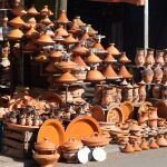 Puesto de venta de platos de cerámica y tagine en vestimentas tradicionales Casablanca Marruecos. Puesto de venta de cerámica tradicional plato de naranja marrón y tagine al estilo tberber Casablanca 