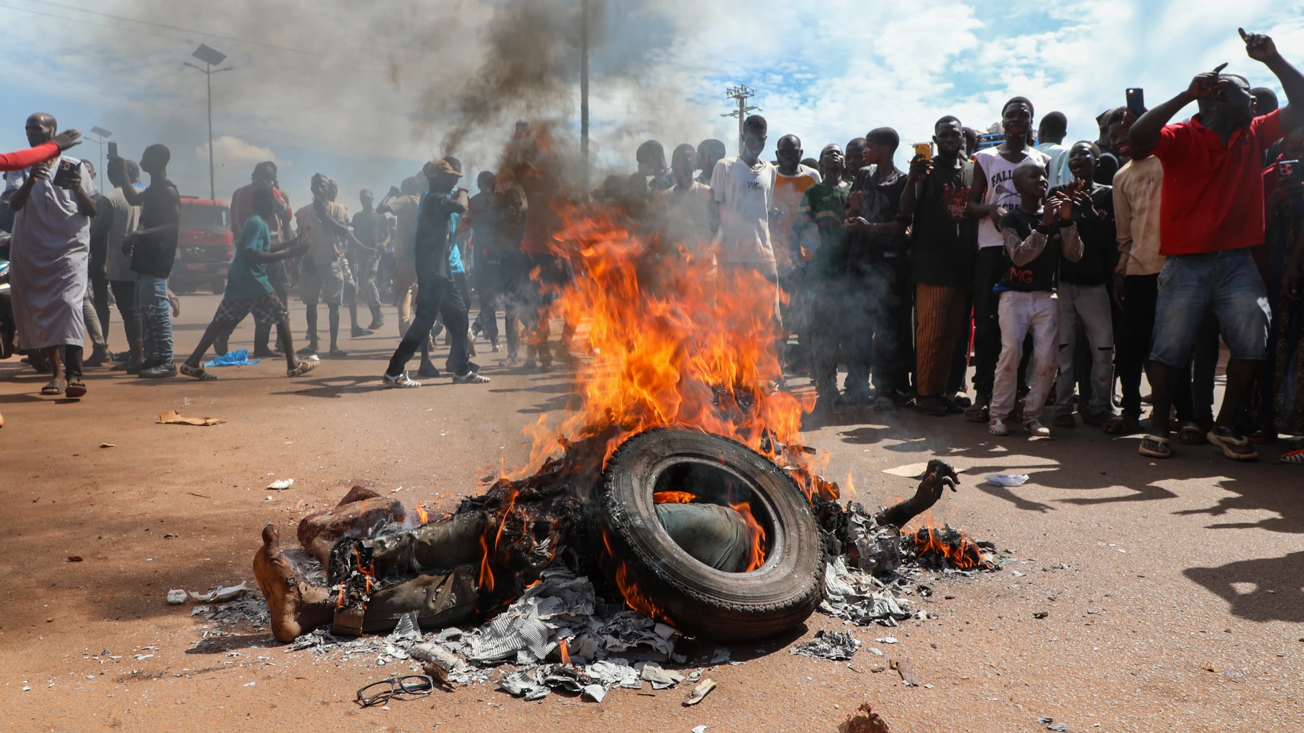 Bamako (Mali), 17/09/2024.- ATTENTION: GRAPHIC CONTENT Local residents watch the body of a man burned alive after being suspected of being an attacker in Bamako, Mali, 17 September 2024. According to the General Staff of the Armed Forces, a group of terrorists attempted to infiltrate the Feladie gendarmerie school on the outskirts of the capital early on 17 September morning. The military government of Mali has been fighting rebel groups since taking power in a coup in 2021. (Terrorista, Golp...