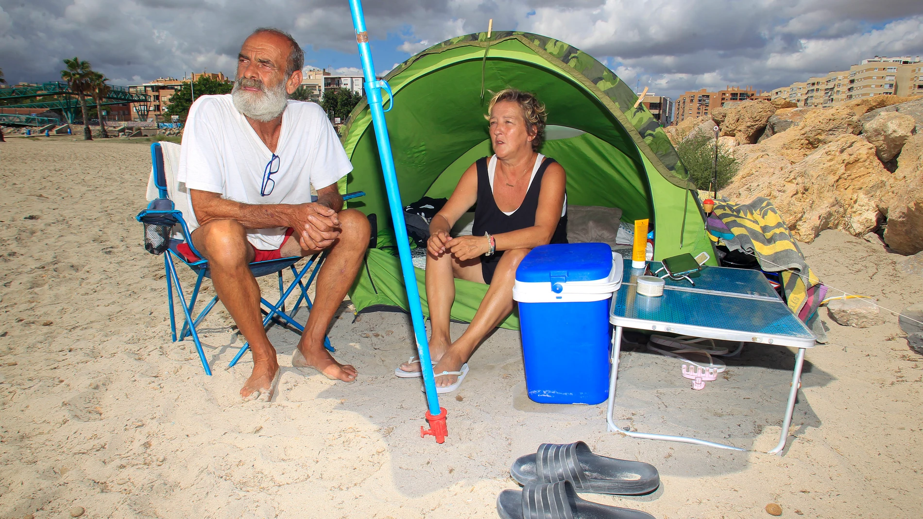 La pareja formada por José Vicente Roca y Charo Ortiz posa junto a hogar en la playa de San Gabriel (Alicante) donde duermen desde el pasado 19 de julio porque no pueden acceder a una vivienda a un precio social a un precio asequible.