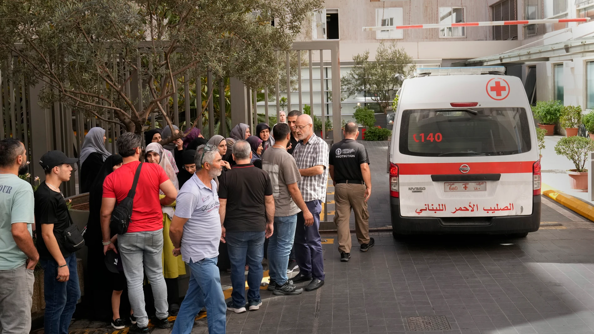 Lebanese Red Cross ambulance passes next of the families of victims who were injured on Monday by their exploding handheld pagers, at the emergency entrance of the American University hospital, in Beirut, Lebanon, Wednesday, Sept. 18, 2024. (AP Photo/Hussein Malla)