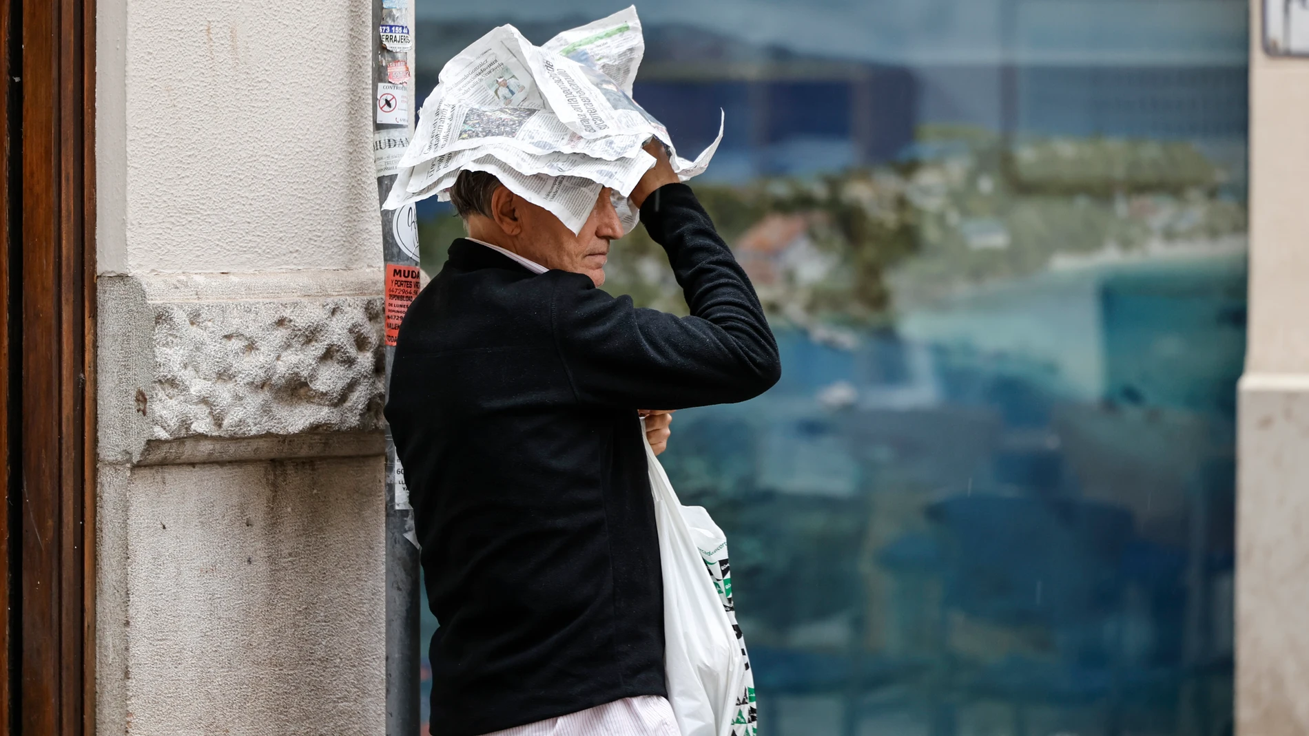 GRAFCVA2985. VALÈNCIA, 19/09/2024.- Un hombre trata de protegerse de la lluvia con unas hojas de periódico este jueves en València. Diez comunidades continúan este jueves con aviso por lluvias o tormentas, con mayor incidencia en la Comunitat Valenciana, donde persiste la alerta naranja (riesgo importante) por lluvias que acumularán hasta 40 litros en una hora. EFE/Biel Aliño