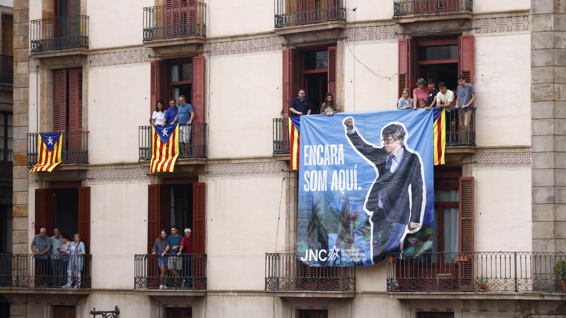 Miembros de las Juventudes Nacionalistas de Cataluña (JNC) cuelgan una pancarta alusiva al ex presidente Carles Puigdemont durante la primera diada castellera de la Mercè 2024 en la Plaça de Sant Jaume de Barcelona durante las fiestas de La Mercè.