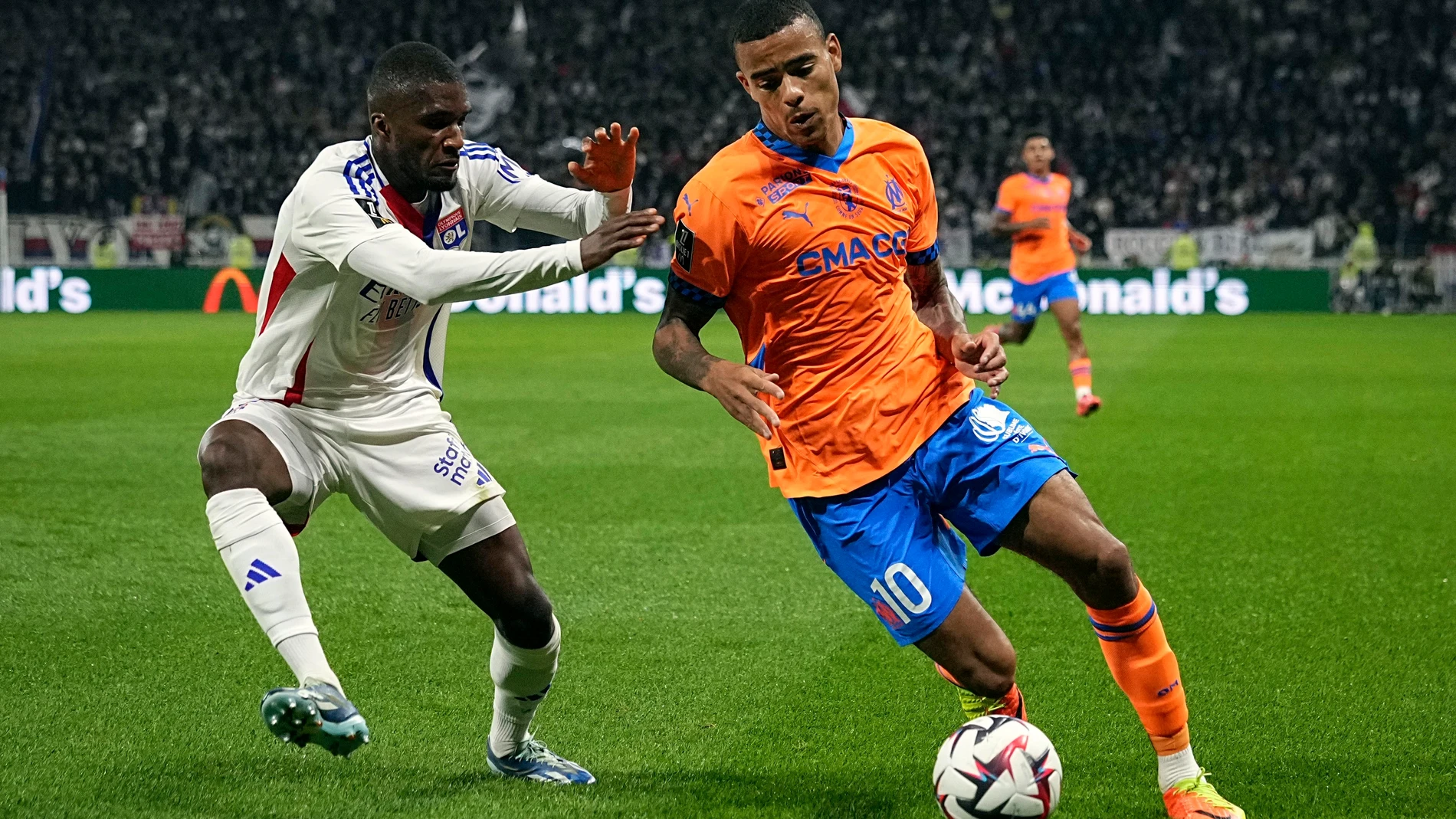 Marseille's Mason Greenwood, right, challenges Lyon's Clinton Mata for the ball during a French League One soccer match at the Groupama stadium in Decines, outside Lyon, France, Sunday, Sept. 22, 2024. (AP Photo/Laurent Cipriani)