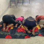 Cuatro niños rezan en el aula de un colegio habilitado como albergue para desplazados en Bir Hassan, a las afueras de Beirut, tras huir de sus hogares debido a la campaña de bombardeados iniciada el lunes por Israel contra el Líbano. Samira y Abed sopesan sus opciones mirando al maletero de un coche cargado de bártulos, que han estacionado en el aparcamiento de uno de los más de 150 colegios habilitados como albergues para desplazados