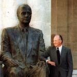 El rey Juan Carlos posa junto a la estatua que le reproduce y que descubrió hoy en el Patio Herrerano del antiguo Monasterio de San Benito el Real