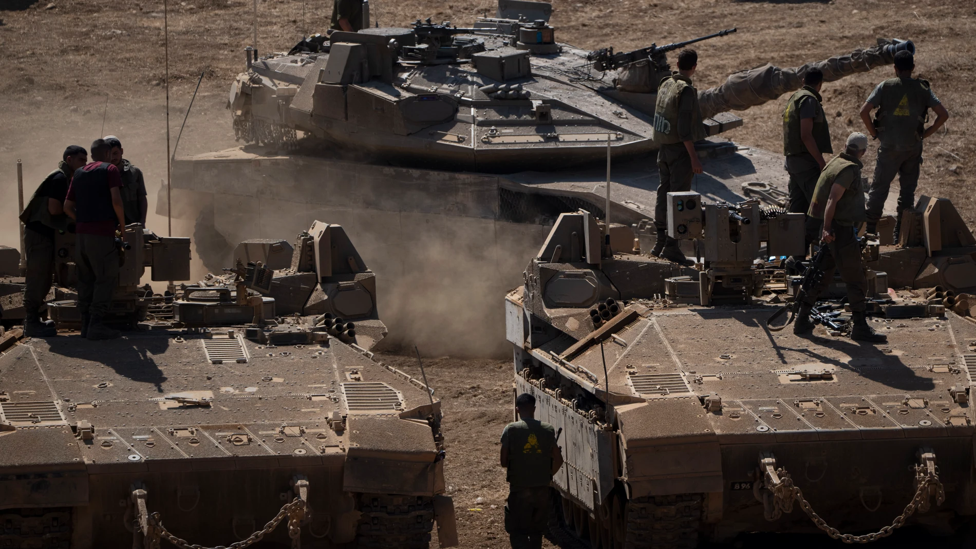 An Israeli tank moves next to soldiers as they stand atop of armoured personnel carriers (APC), in northern Israel, Monday, Sept. 30, 2024. (AP Photo/Leo Correa)