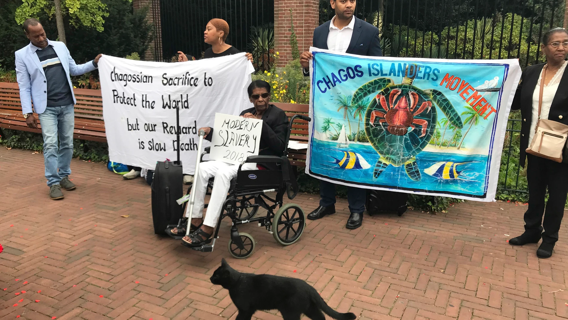 FILE - Protesters hold banners outside the World Court in The Hague, Netherlands, Monday, Sept. 3, 2018, where judges listen to arguments in a case on whether Britain illegally maintains sovereignty over the Chagos Islands. (AP Photo/Mike Corder, File)