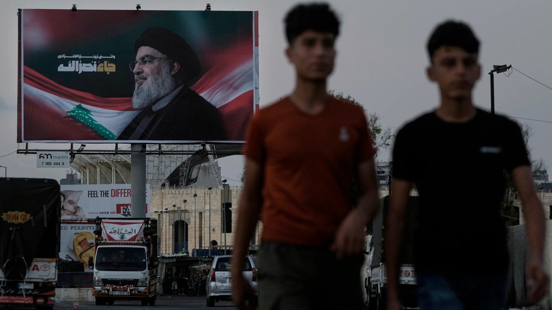 People walk past a billboard with a picture of the late Lebanon's Hezbollah leader Sayyed Hassan Nasrallah displayed on a Beirut airport highway, Saturday, Oct. 5, 2024. (AP Photo/Bilal Hussein)