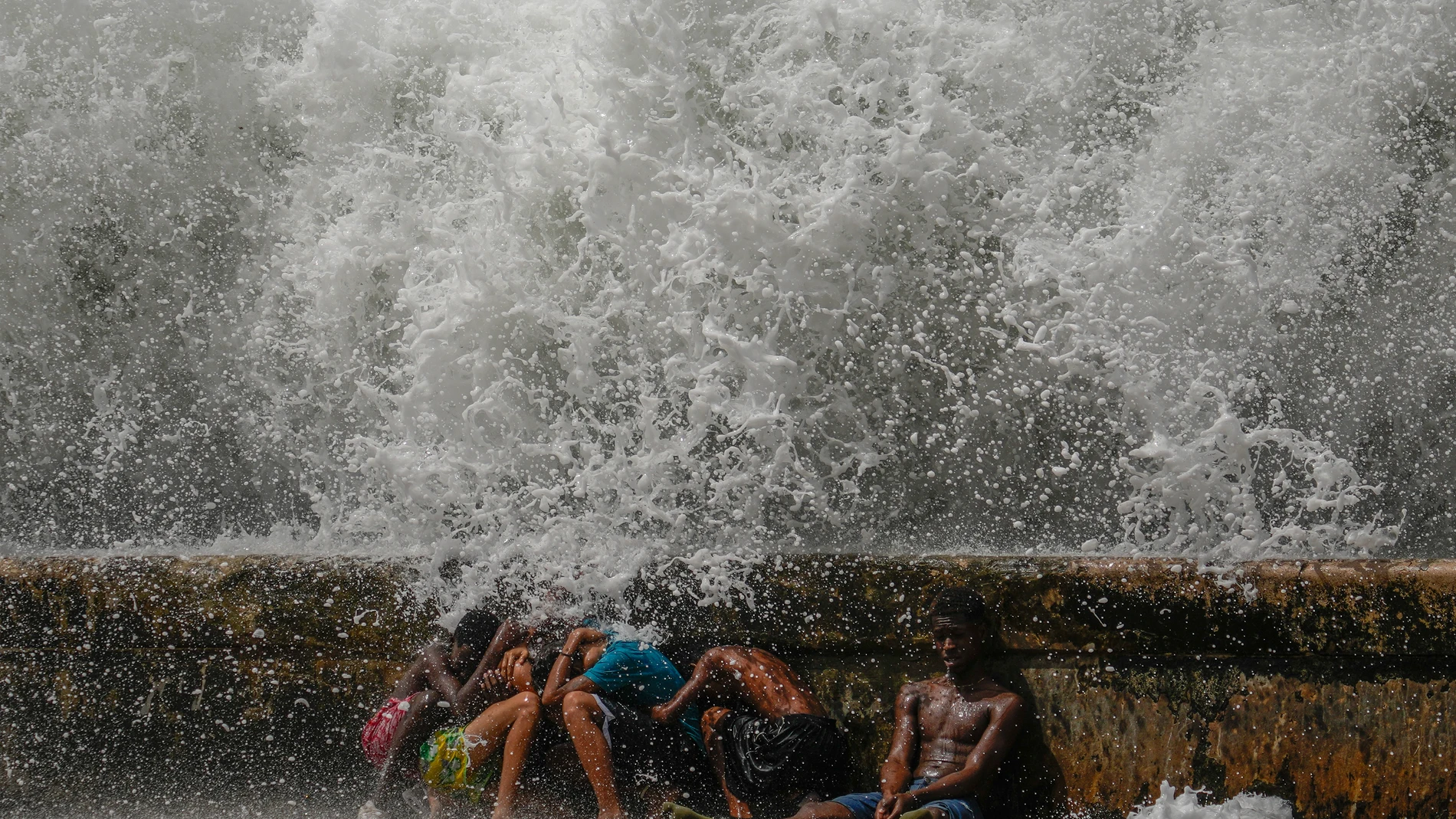 Youths duck behind the Malecon seawall as they play in the surf brought by Hurricane Milton passing through the Gulf of Mexico, in Havana, Cuba, Wednesday, Oct. 9, 2024. (AP Photo/Ramon Espinosa)