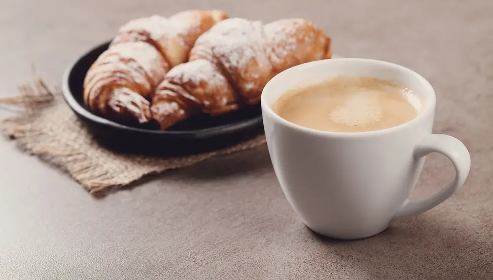 Una taza de café delante de un cruasán