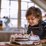 Un niño sopla las velas de una tarta de cumpleaños 