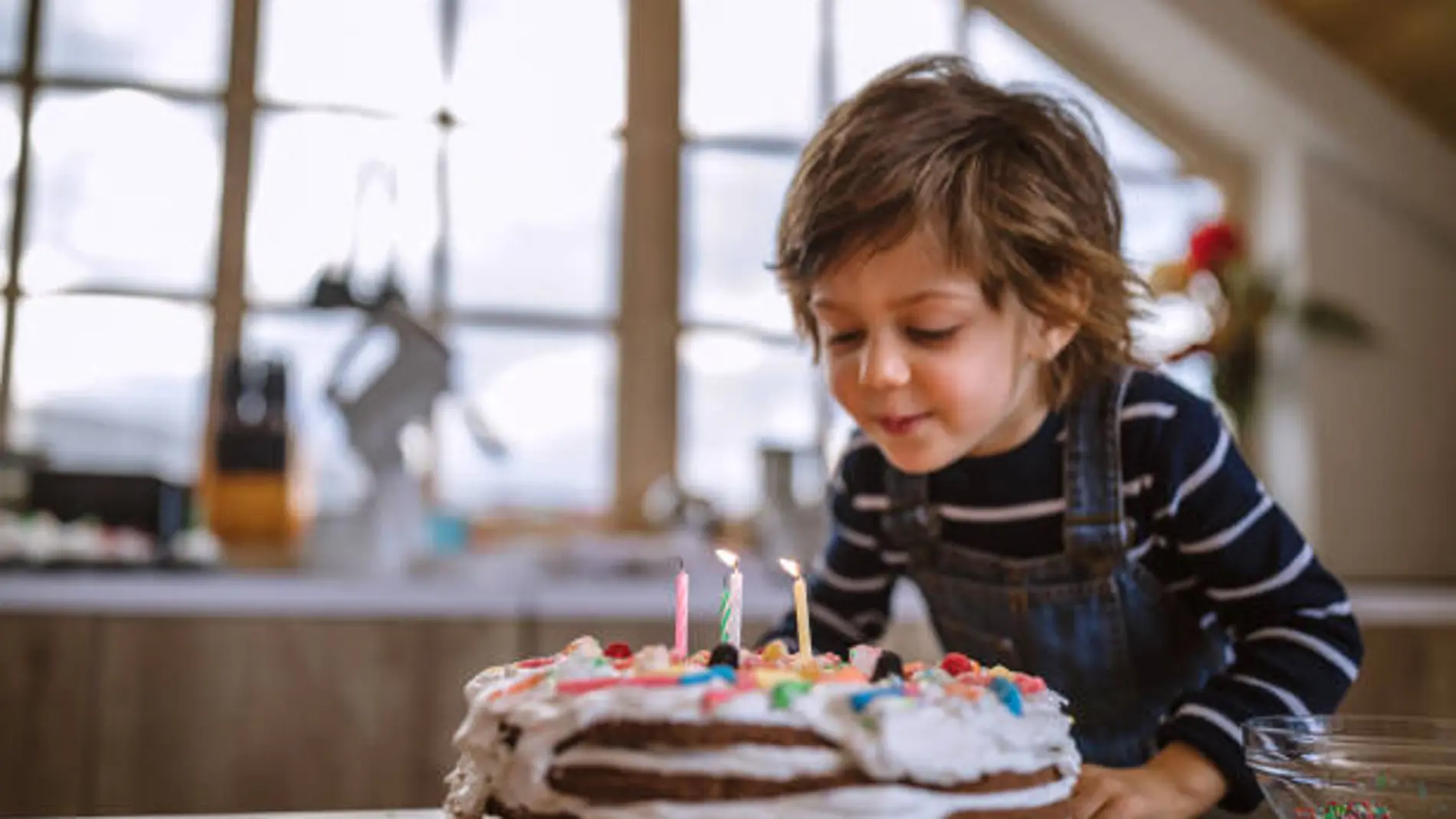 Un niño sopla las velas de una tarta de cumpleaños