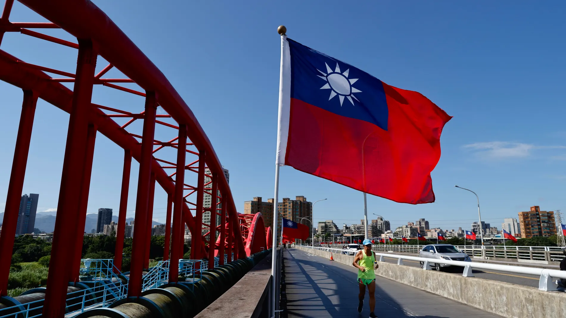 Taipei (Taiwan), 15/10/2024.- A person runs past a Taiwan national flag on a street in Taipei, Taiwan, 15 October 2024. On 14 October, China flew a record 125 warplanes near Taiwan during the 'Joint Sword 2024-B' military drills, according to Taiwan's Ministry of National Defense. EFE/EPA/RITCHIE B. TONGO