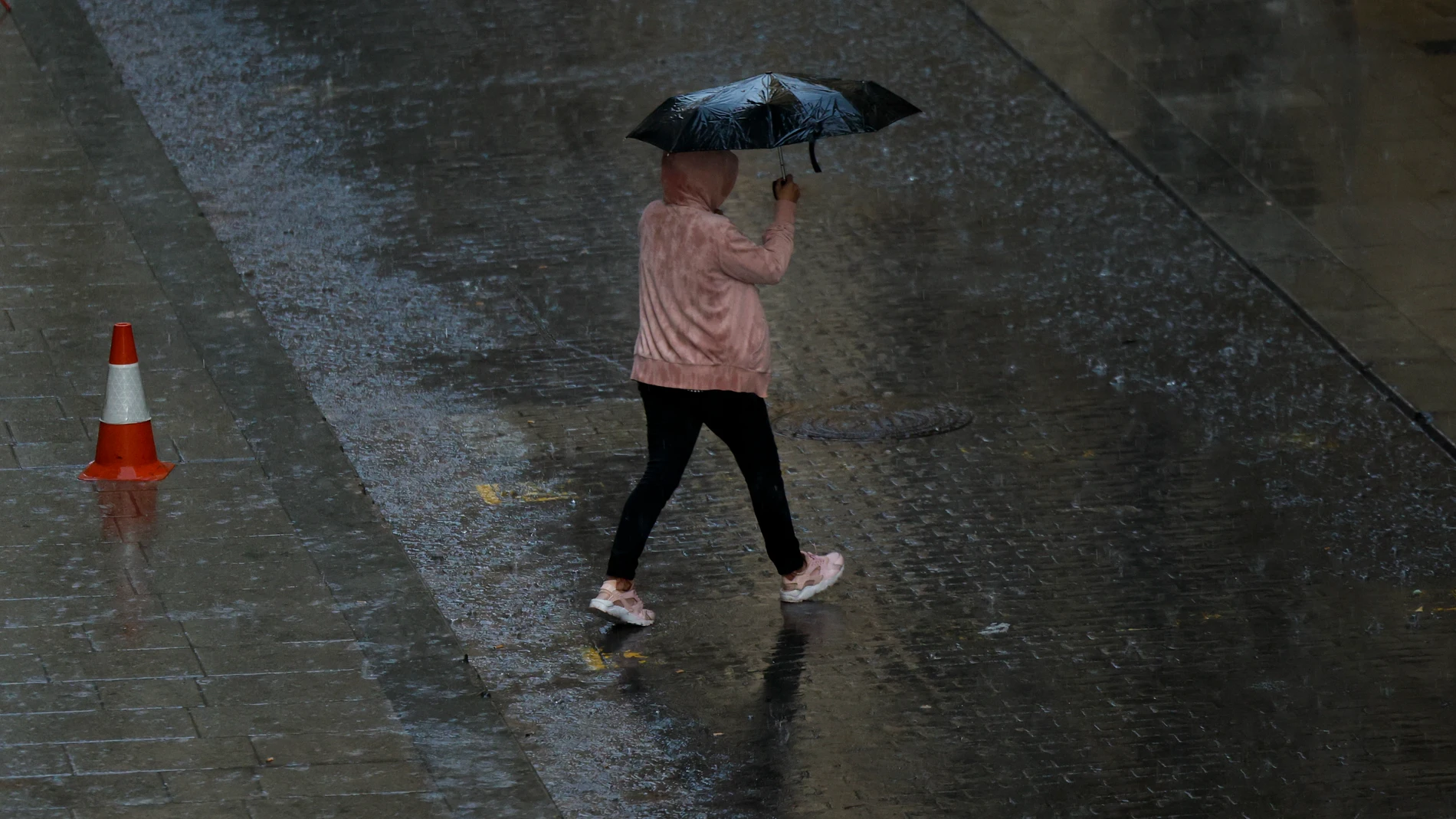 GRAFCVA3474. VALENCIA, 15/10/2024.- Una persona se protege de la lluvia con un paraguas cuando las precipitaciones que este martes han caído en la Comunitat Valenciana han superado esta tarde los 100 litros por metro cuadrado en las comarcas de l'Alcalatén y l'Alt Maestrat, en la provincia de Castellón, y las de la Serranía y Camp de Túria, en la provincia de Valencia, según la Asociación Valenciana de Meteorología (Avamet). EFE/Biel Aliño