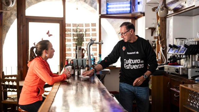 Marina Albesa, conversa con Pedro Silvestre, quien forma parte del proyecto Àmbit de reinserción sociolaboral, en el bar del Mesón de Herbers donde los integrantes del proyecto aprenden a gestionar un negocio de hosteleria