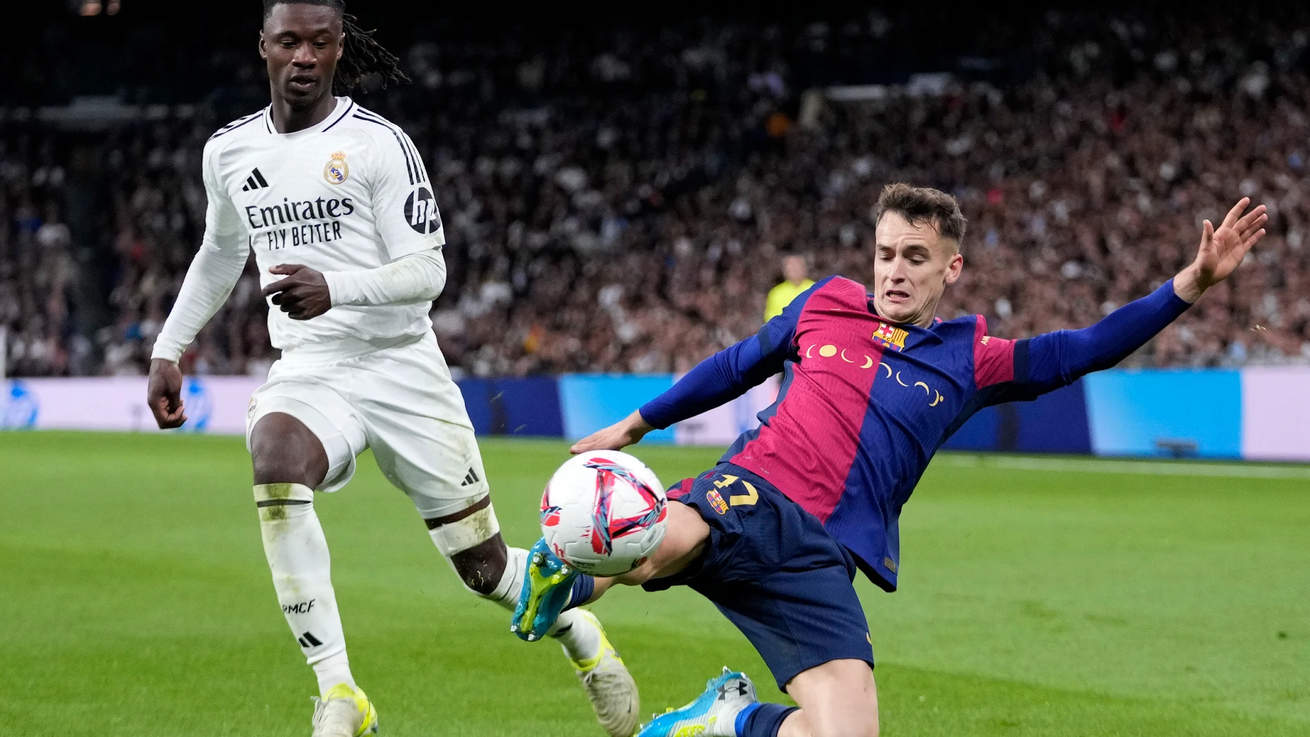 Real Madrid's Eduardo Camavinga fights for the ball against Barcelona's Marc Casado during a Spanish La Liga soccer match between Real Madrid and Barcelona at the Santiago Bernabeu stadium in Madrid, Spain, Saturday, Oct. 26, 2024. (AP Photo/Bernat Armangue)