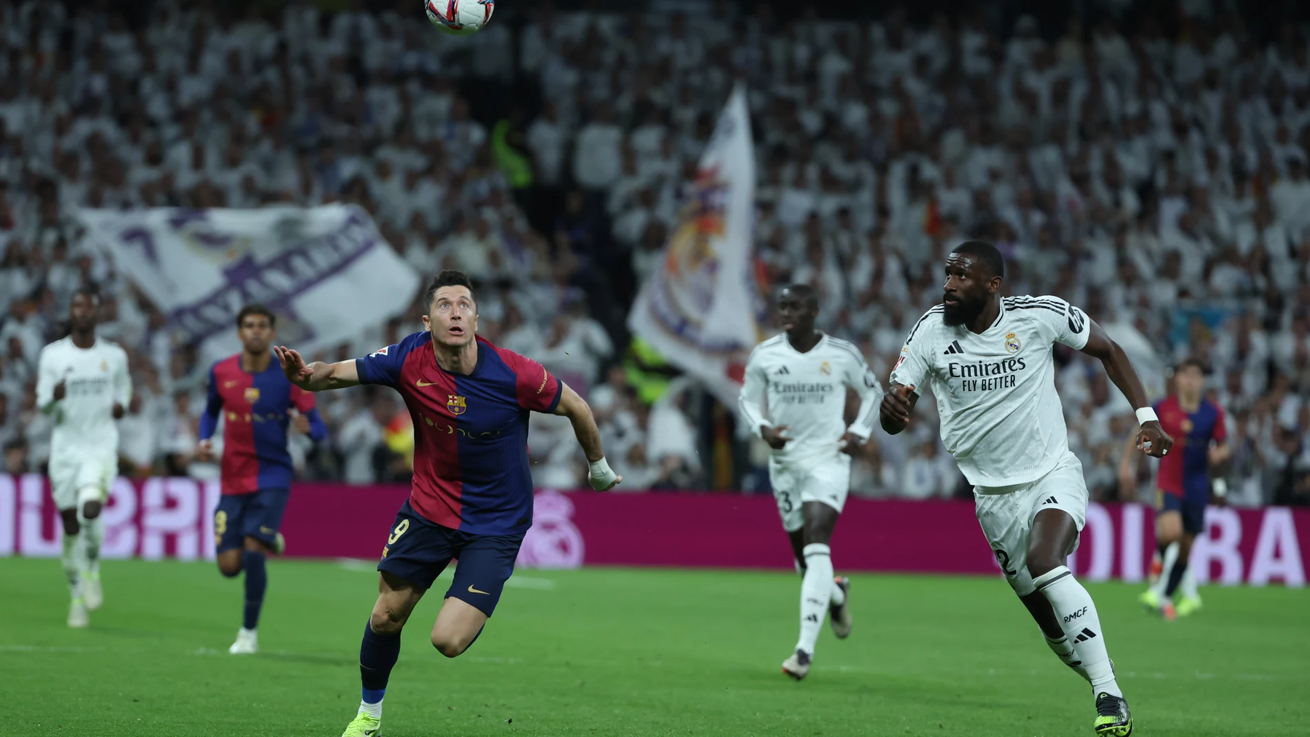 MADRID, 26/10/2024.- El defensa del Real Madrid Antonio Rudiger (d) persigue el balón con Robert Lewandowski, del FC Barcelona, durante el partido de la jornada 11 de LaLiga EA Sports entre el Real Madrid y el FC Barcelona, este sábado en el estadio Santiago Bernabéu, en Madrid. EFE/Kiko Huesca