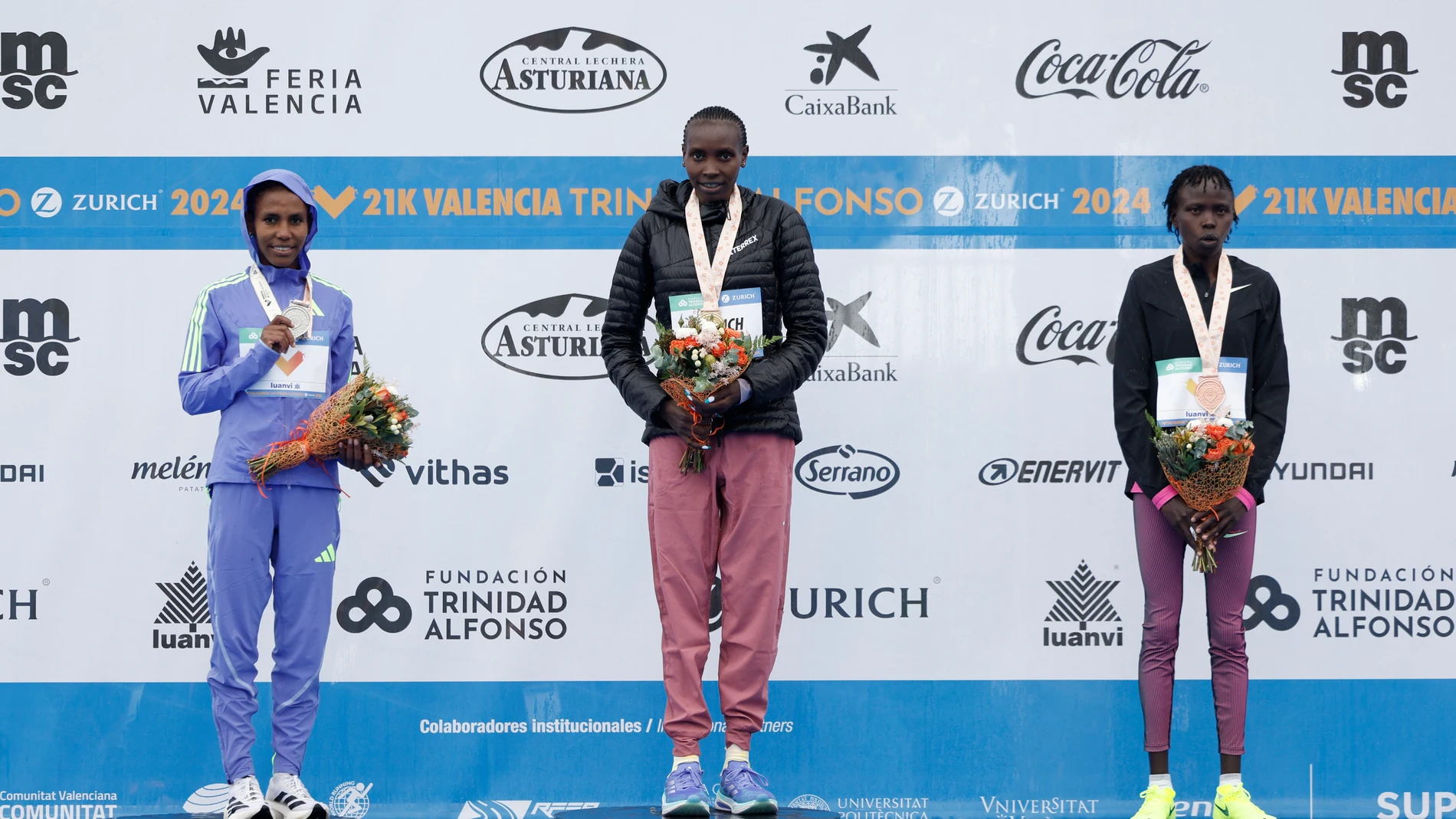 La keniana Agnes Ngetich (c) celebra su victoria junto a la etíope Fotyen Tesfay (i), segunda posición, y la keniana Lilian Kasait , tercera posición, tras la media maratón de Valencia celebrada, este domingo, en Valencia.