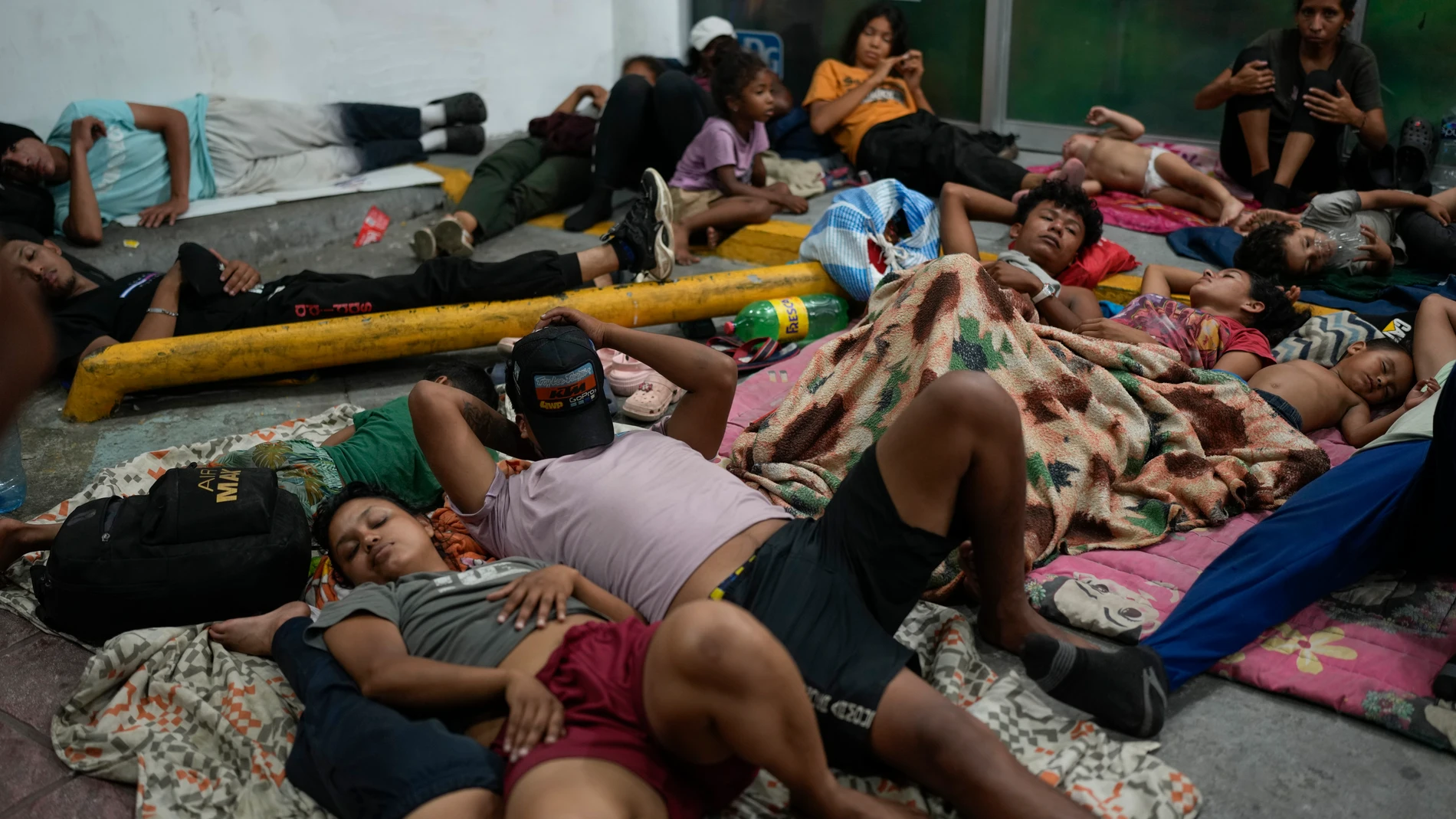 Migrants rest in front of a paint shop in Tapachula, Mexico, Sunday, Oct. 27, 2024. (AP Photo/Matias Delacroix)