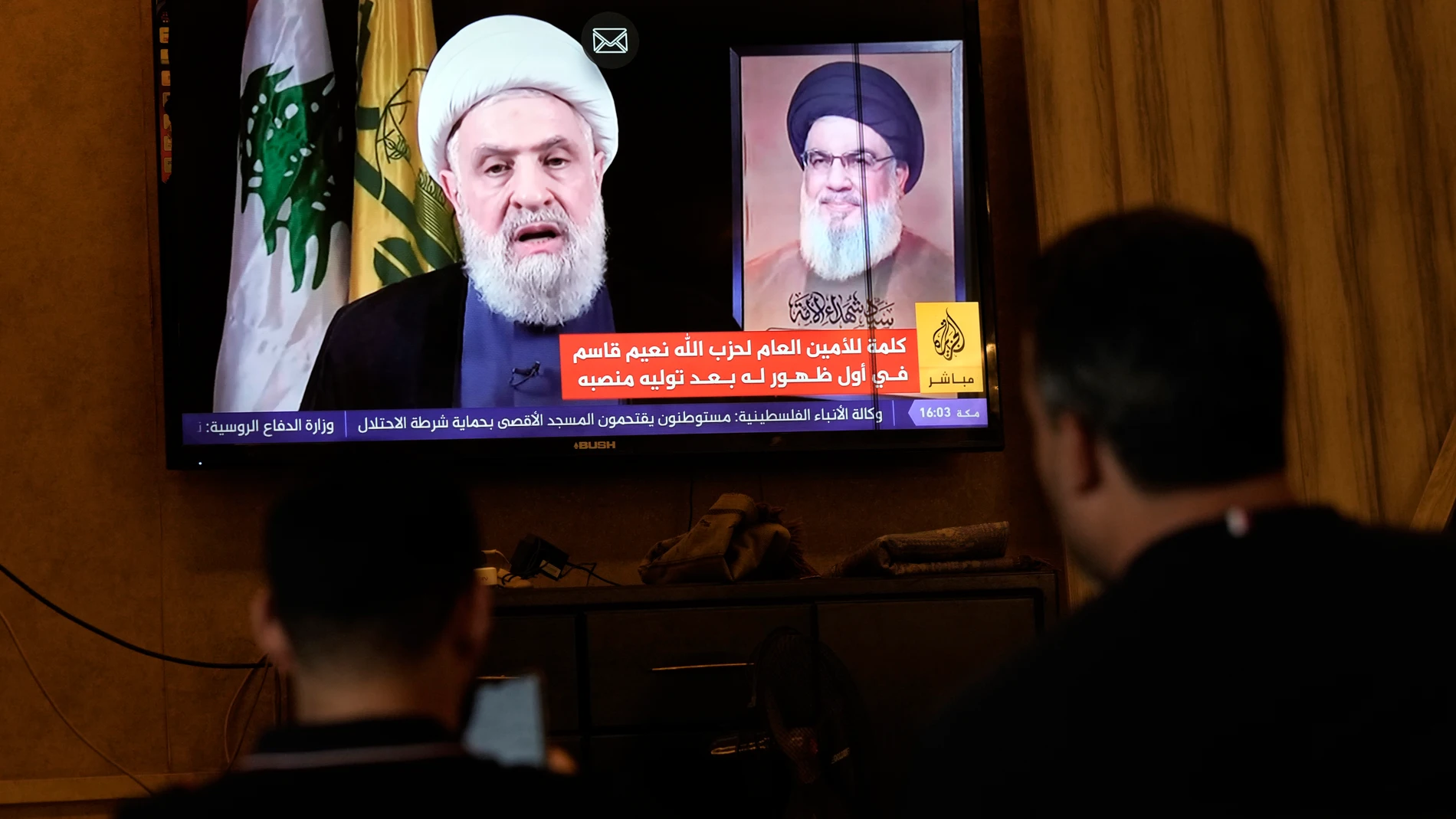 People watch Hezbollah's newly named leader Naim Kassem delivering a televised speech, in the southern port city of Sidon, Lebanon, Wednesday, Oct. 30, 2024. (AP Photo/Bilal Hussein)