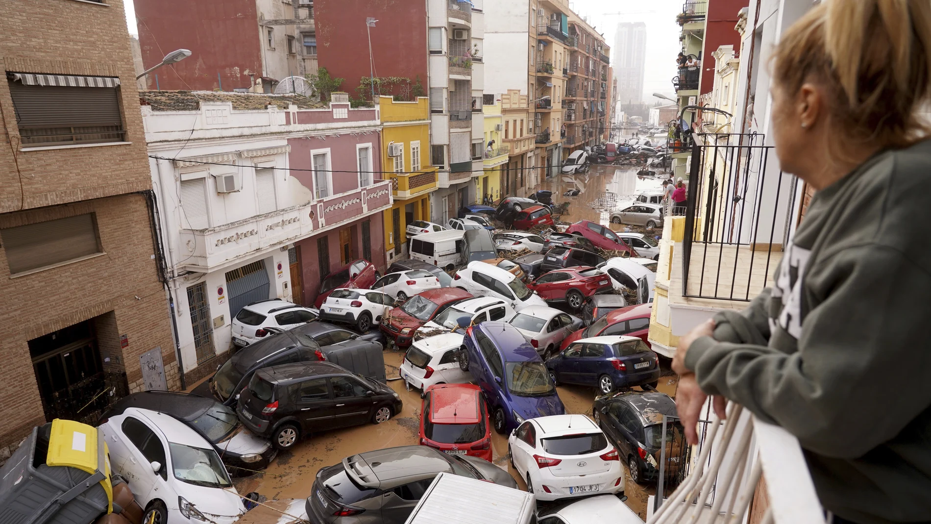 A woman looks out from her balcony as vehicles are trapped in the street after flooding in Valencia, Wednesday, Oct. 30, 2024.