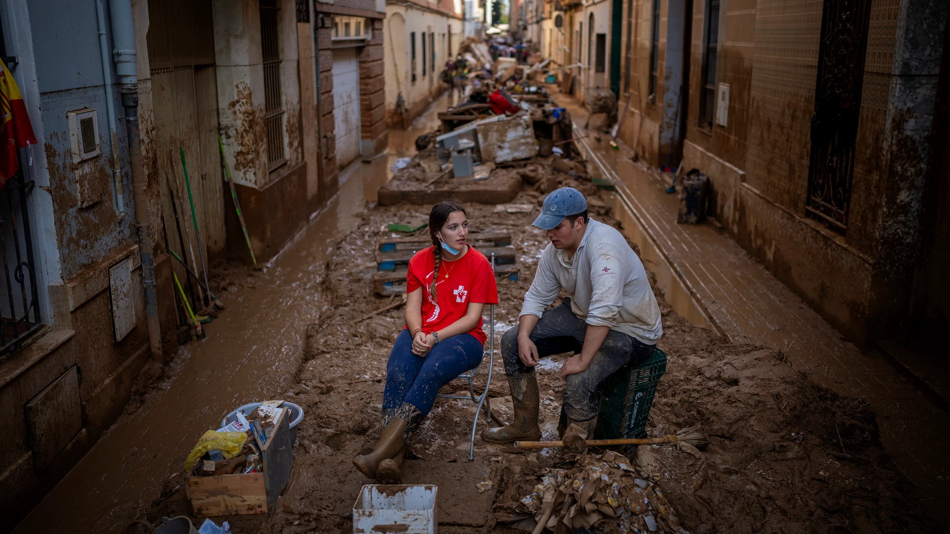 Volunteers take a break while clearing mud from the streets in an area affected by floods in Paiporta, Valencia, Spain, Tuesday, Nov. 5, 2024. (AP Photo/Emilio Morenatti)