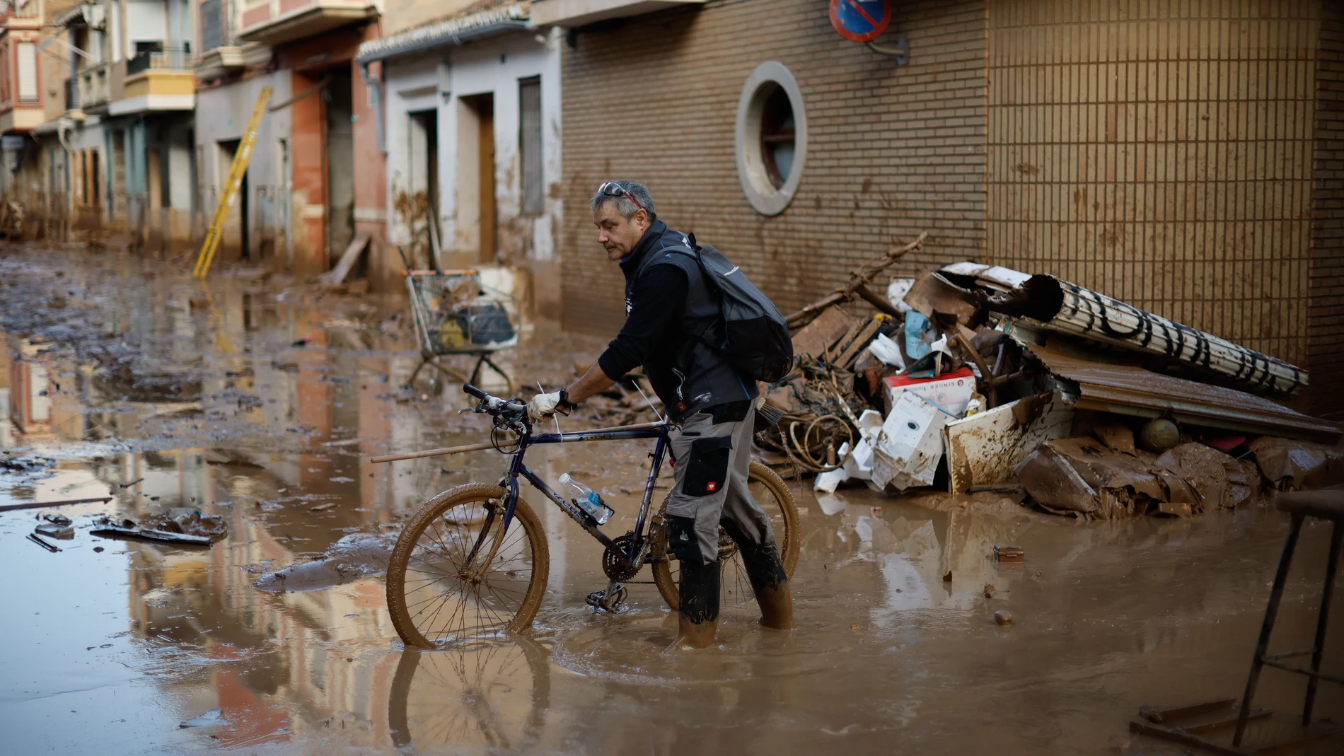 FOTODELDÍA PAIPORTA (VALENCIA), 07/11/2024.- Un voluntario acude en bicicleta a la localidad de Paiporta, este jueves. Voluntarios, fuerzas de seguridad, bomberos, militares y vecinos de las localidades más afectadas por la dana continúan con las tareas de limpieza mientras los equipos de rescate siguen rastreando la zona para intentar localizar a las personas que aún sigue desaparecidas. EFE/Biel Aliño