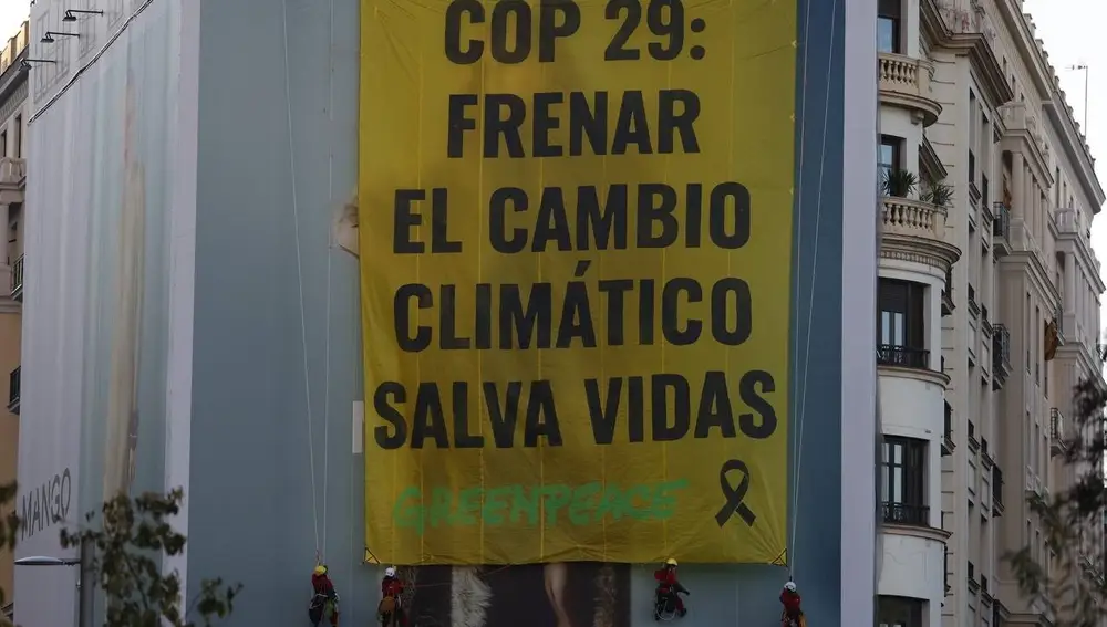 Activistas de Greenpeace despliegan la pancarta en la plaza de España de Madrid.
