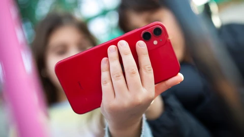 Niños con el teléfono móvil a la puertas de un colegio.