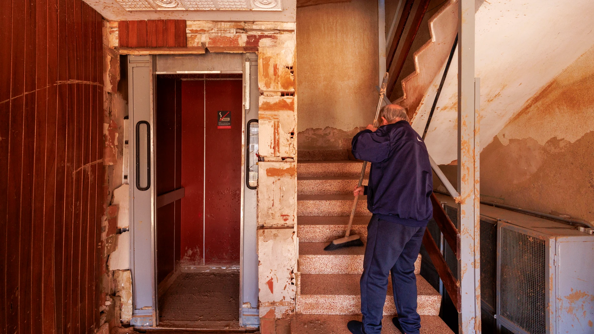 PAIPORTA (VALENCIA) 20/11/2024.- Miguel barre las escaleras del portal de su casa de Paiporta, ahora especialmente transitadas ya que la dana del pasado 29 de octubre se llevó consigo la puerta del ascensor de su edificio y muchos vecinos de edad avanzada o con movilidad reducida de este municipio, afrontan el reto extra de poder salir de su vivienda y recuperar algo de pulso a la calle. EFE/Villar López