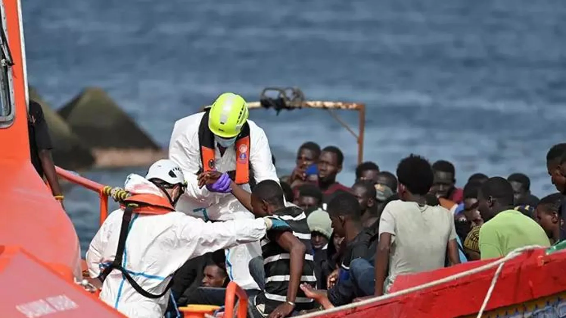 Trabajadores ayudan a los migrantes que llegan en patera al puerto de La Restinga, trasladados por Salvamento Marítimo, a 26 de julio de 2024, en El Hierro, Canarias