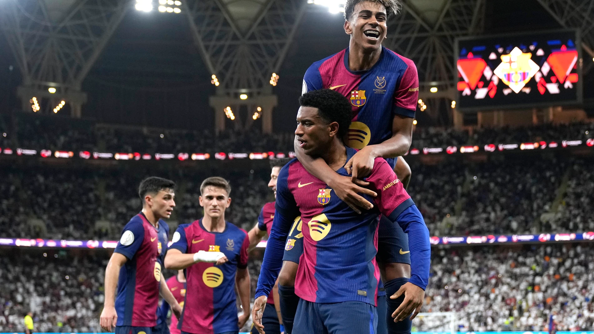 Barcelona's Alejandro Balde and Barcelona's Lamine Yamal, top, react during the Spain Super Cup final soccer match between Real Madrid and Barcelona at King Abdullah Stadium in Jeddah, Saudi Arabia, Sunday, Jan. 12, 2025. (AP Photo/Altaf Qadri)