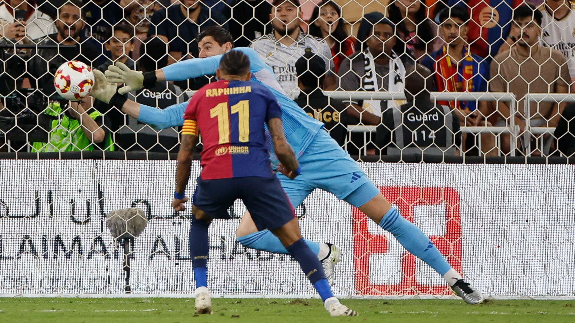 YEDA (ARABIA SAUDÍ), 12/01/2025.- El guardameta belga Thibaut Courtois, del Real Madrid, detiene el lanzamiento del delantero brasileño del FC Barcelona Raphinha, durante el partido de la final de la Supercopa de España de fútbol entre el Real Madrid y el FC Barcelona, este domingo en Yeda, Arabia Saudí. EFE/ Alberto Estévez