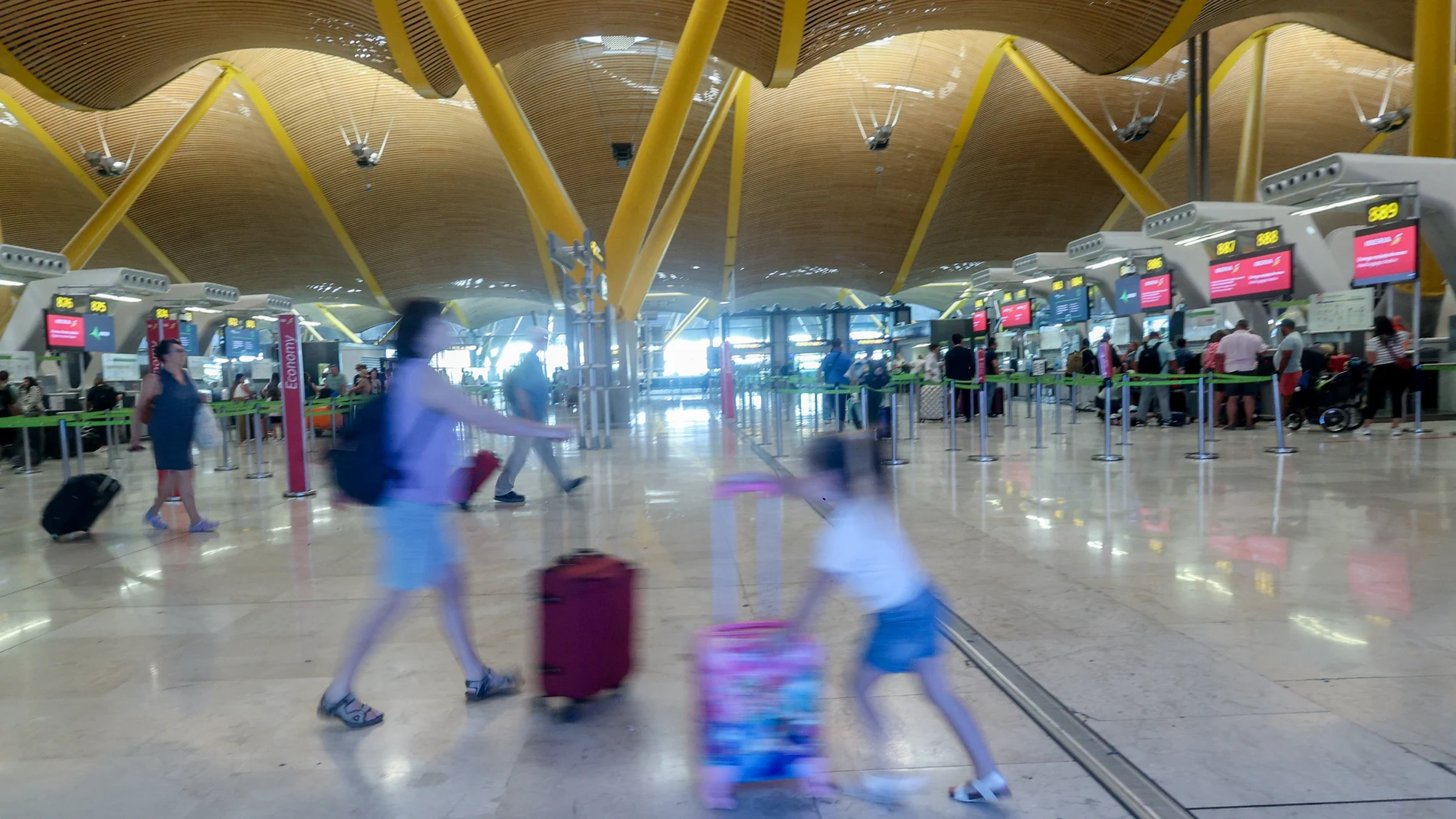 Una mujer y una niña caminan con sus maletas, en la T4, en el aeropuerto Adolfo Suárez Madrid-Barajas, en Madrid (España).