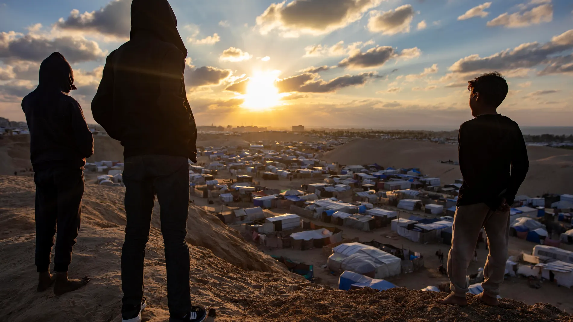 Gaza (---), 18/01/2025.- Palestinians watch the sunset next to a camp for internally displaced people in the southern Gaza Strip, 18 January 2025. A ceasefire between Israel and Hamas will take effect on 19 January 2025. More than 46.000 people have been killed in Gaza since October 2023, when Israel launched a military campaign in response to a cross-border attack by Hamas, in which about 1,200 people were killed and over 200 taken hostage. EFE/EPA/HAITHAM IMAD