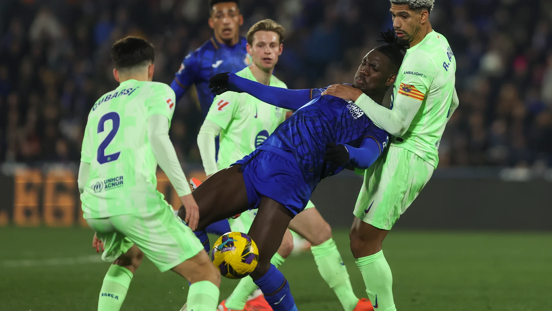 GETAFE (MADRID), 18/01/2025.- El centrocampista nigeriano del Getafe, Chrisantus Uche (c), cae ante el defensa uruguayo del FC Barcelona, Ronald Araujo, durante el encuentro correspondiente a la jornada 20 de Laliga EA Sports que disputan hoy sábado Getafe y FC Barcelona en el Coliseum de Getafe. EFE / Kiko Huesca.