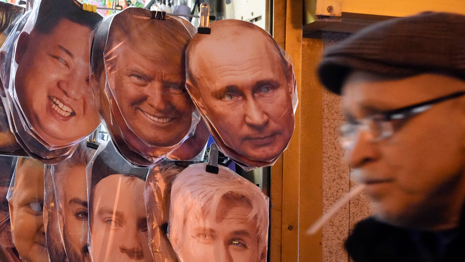 A man walks past face masks depicting North Korean leader Kim Jong Un, US President-elect Donald Trump, center, and Russian President Vladimir Putin, right, hanging among others for sale at a street souvenir shop in St. Petersburg, Russia, Monday, Jan. 20, 2025. (AP Photo/Dmitri Lovetsky)