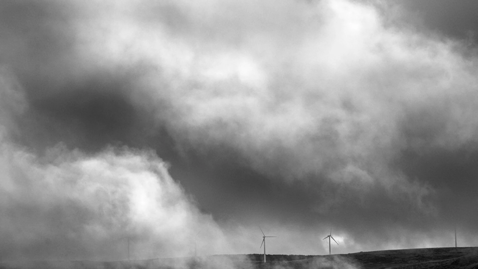 Molino de viento entre nubes del paisaje en la Sierra de Ojos de Albos, Avila.