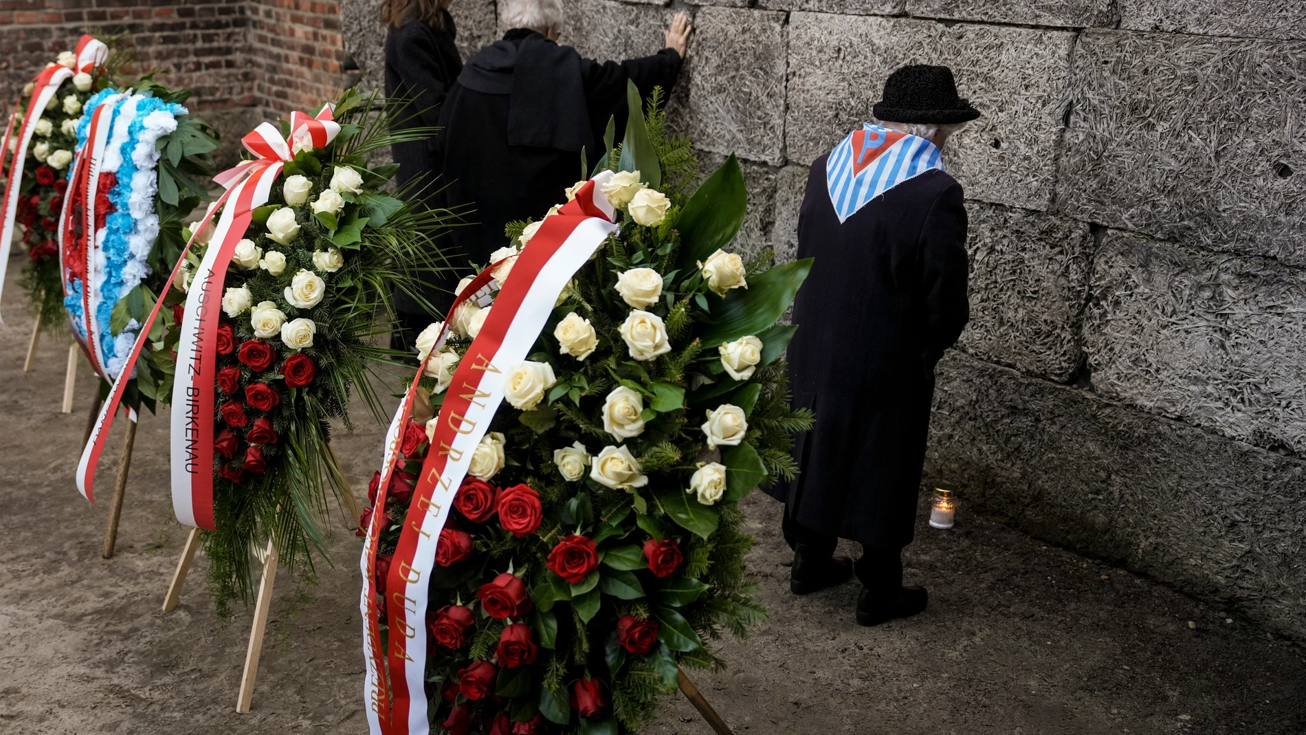 A survivor stands after placing a candle to the Death Wall at the Auschwitz-Birkenau former Nazi German concentration and extermination camp, during a ceremony marking the 80th anniversary of the camp's liberation, in Oswiecim, Poland, Monday, Jan. 27. 2025.(AP Photo/Oded Balilty)