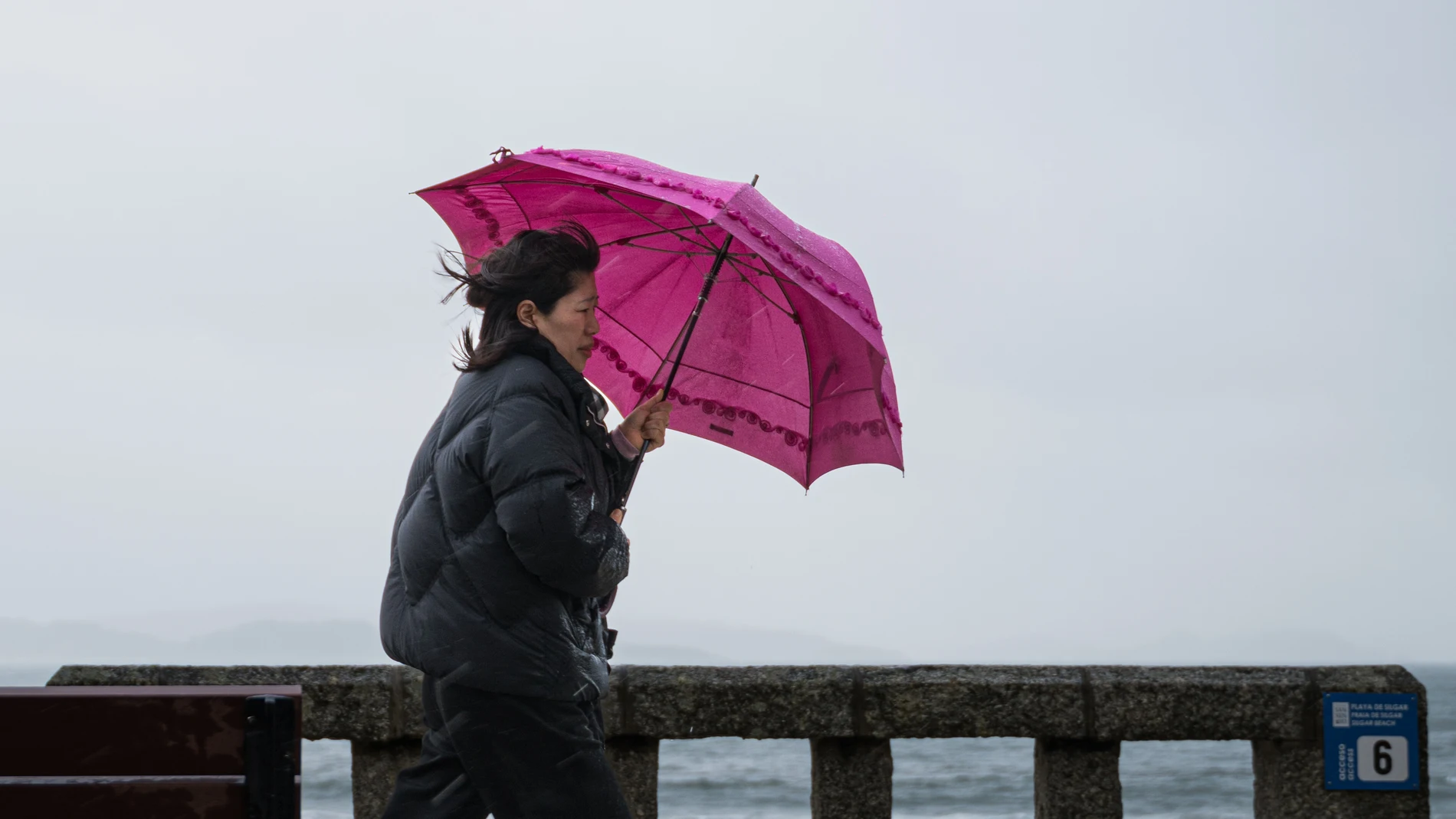 Una mujer se refugia de la lluvia con paraguas