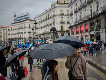 Lluvia en Madrid. Lluvia en Madrid. Turistas se hacen fotos junto a la estatua del oso y el madroño en la madrileña puerta del Sol, La AEMET confirma que lo peor del giro invernal en Madrid está por venir: alerta por nieves, frío y fuertes lluvias. © Alberto R. Roldán / Diario La Razón.03 03 2025