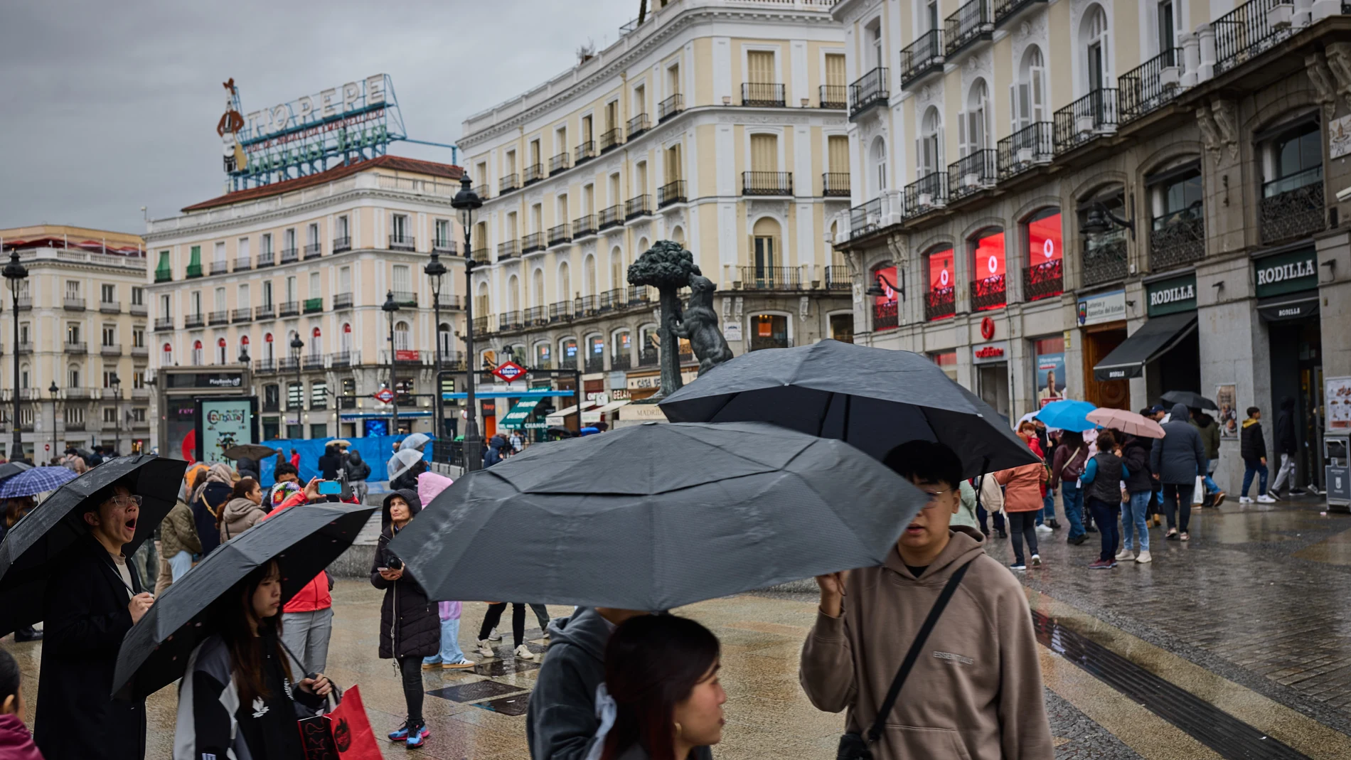 Lluvia en Madrid. Turistas se hacen fotos junto a la estatua del oso y el madroño en la madrileña puerta del Sol, La AEMET confirma que lo peor del giro invernal en Madrid está por venir: alerta por nieves, frío y fuertes lluvias. © Alberto R. Roldán / Diario La Razón.03 03 2025